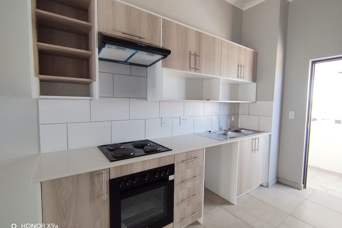 Modern kitchen featuring light wood-finish cabinetry, built-in oven and hob, extractor fan, and a clean tiled backsplash.
