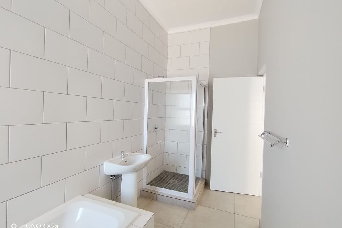 A clean, modern bathroom featuring a pedestal basin, a separate shower enclosure with tiled walls, and a built-in bathtub.