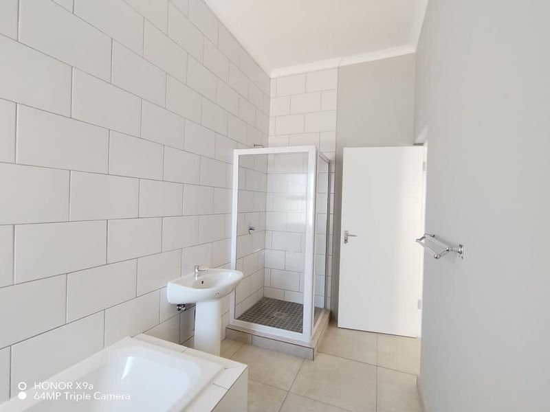 A clean, modern bathroom featuring a pedestal basin, a separate shower enclosure with tiled walls, and a built-in bathtub.