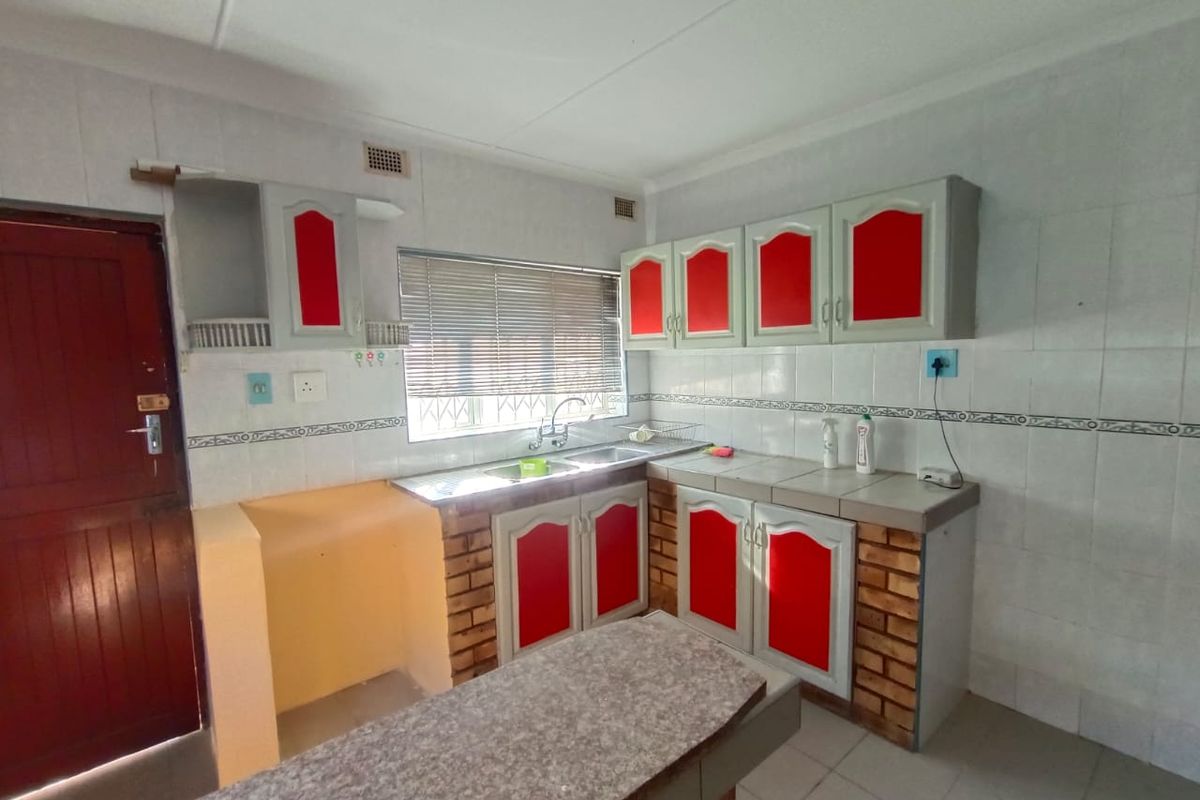 A functional kitchen featuring tiled splashbacks, built-in cabinetry, a double sink, and a central island, offering potential for modern renovation.