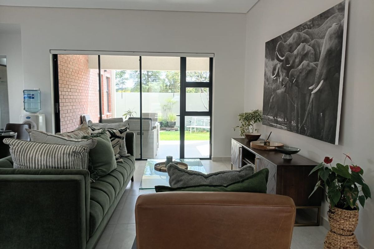 A bright living room featuring large sliding glass doors that provide seamless access to the outdoor patio and garden area.