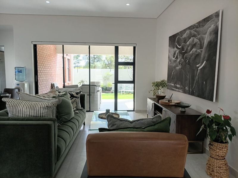 A bright living room featuring large sliding glass doors that provide seamless access to the outdoor patio and garden area.