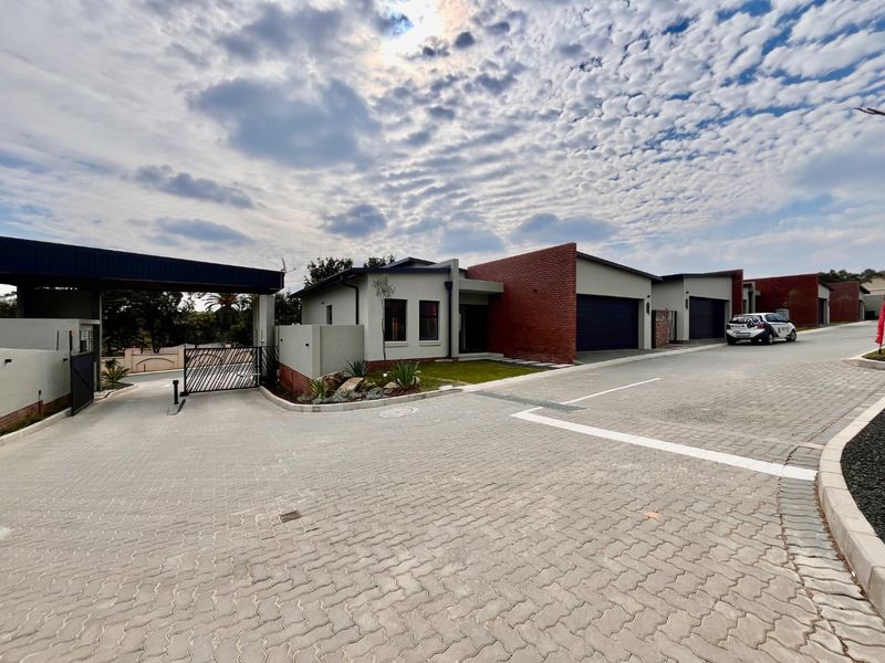 Modern residential complex entrance featuring paved driveway, brick facade architecture, and secure automated garage access.