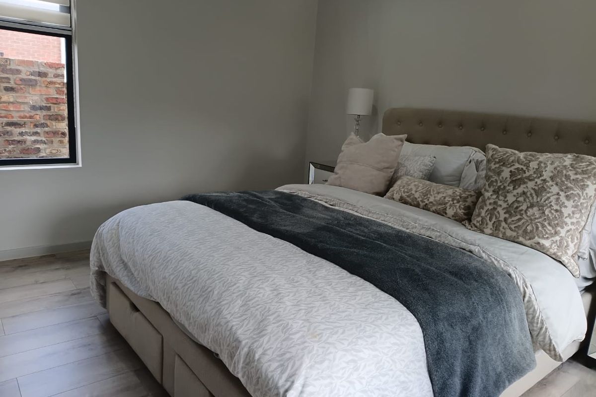 A well-maintained bedroom featuring light-toned laminate flooring and a neutral color palette, providing a clean and comfortable living space.