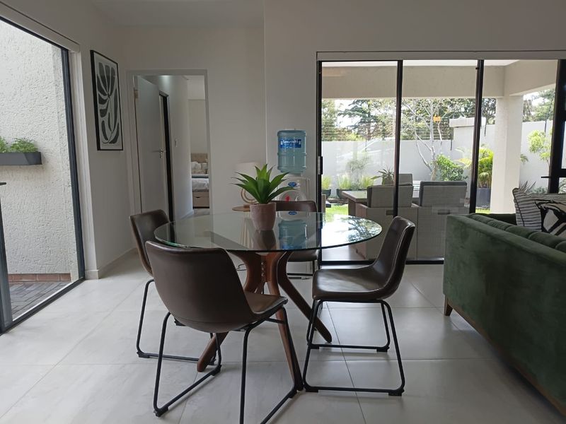 Bright open-plan living and dining area featuring large sliding glass doors that provide seamless access to the outdoor patio and garden.