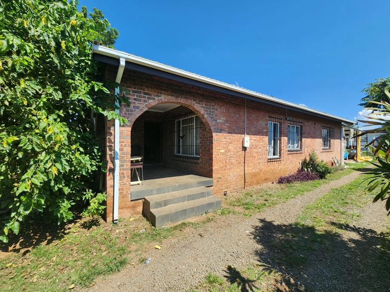 A face brick exterior facade featuring an arched covered porch entrance, tiled steps, and security bars on the windows.