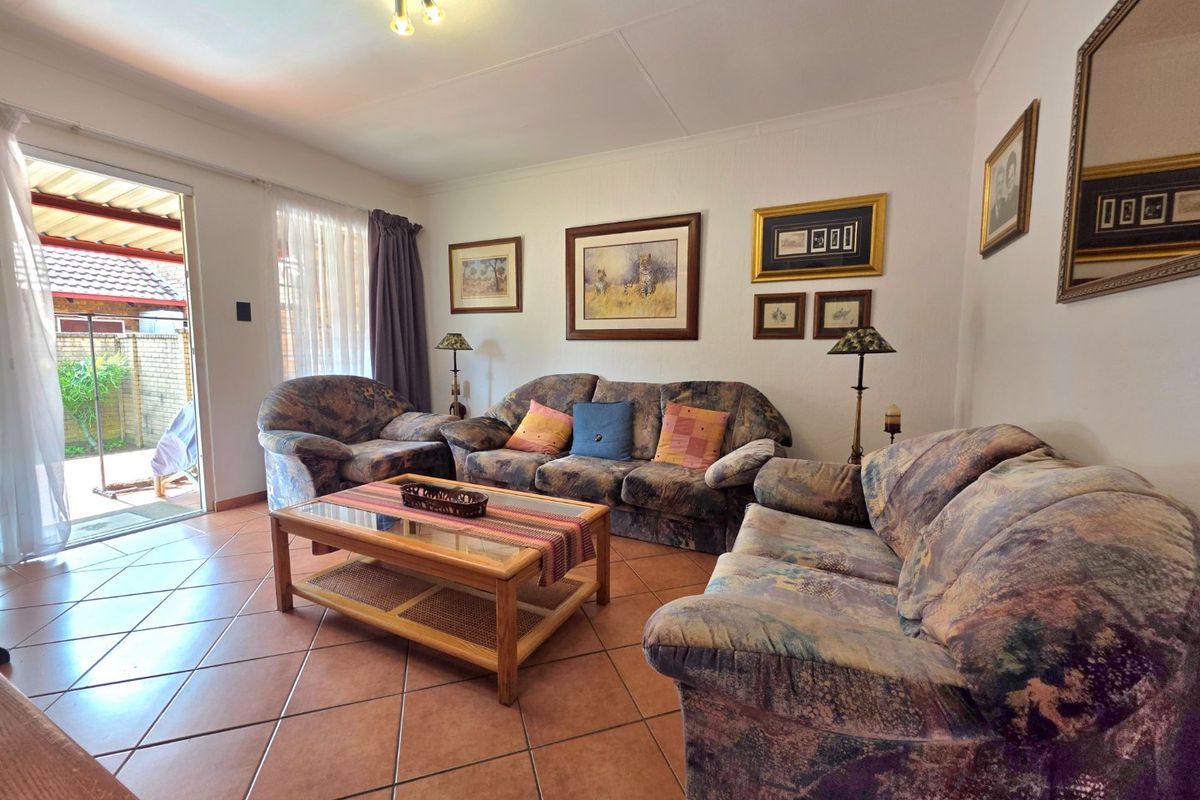A comfortable living room featuring terracotta floor tiles and direct access to an outdoor patio area through a sliding glass door.