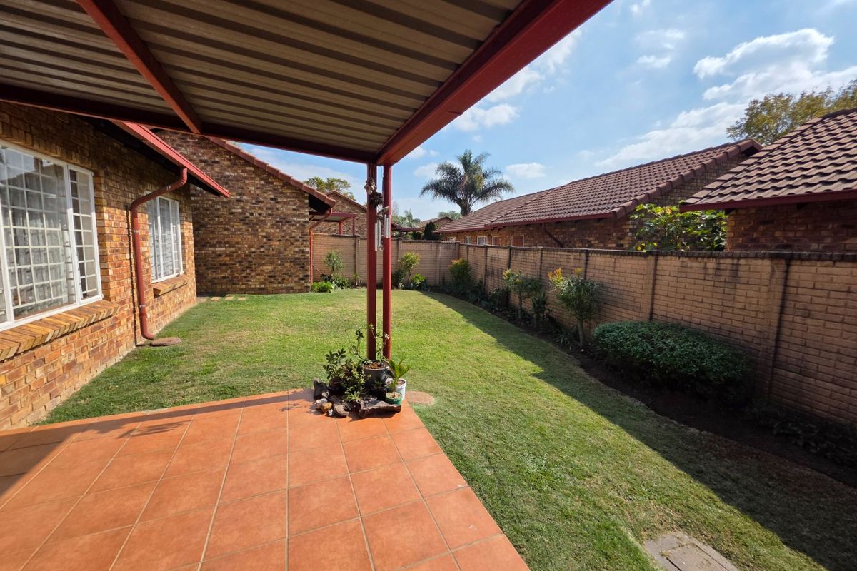 A private rear garden featuring a covered tiled patio, facebrick exterior walls, and a secure perimeter brick boundary wall.