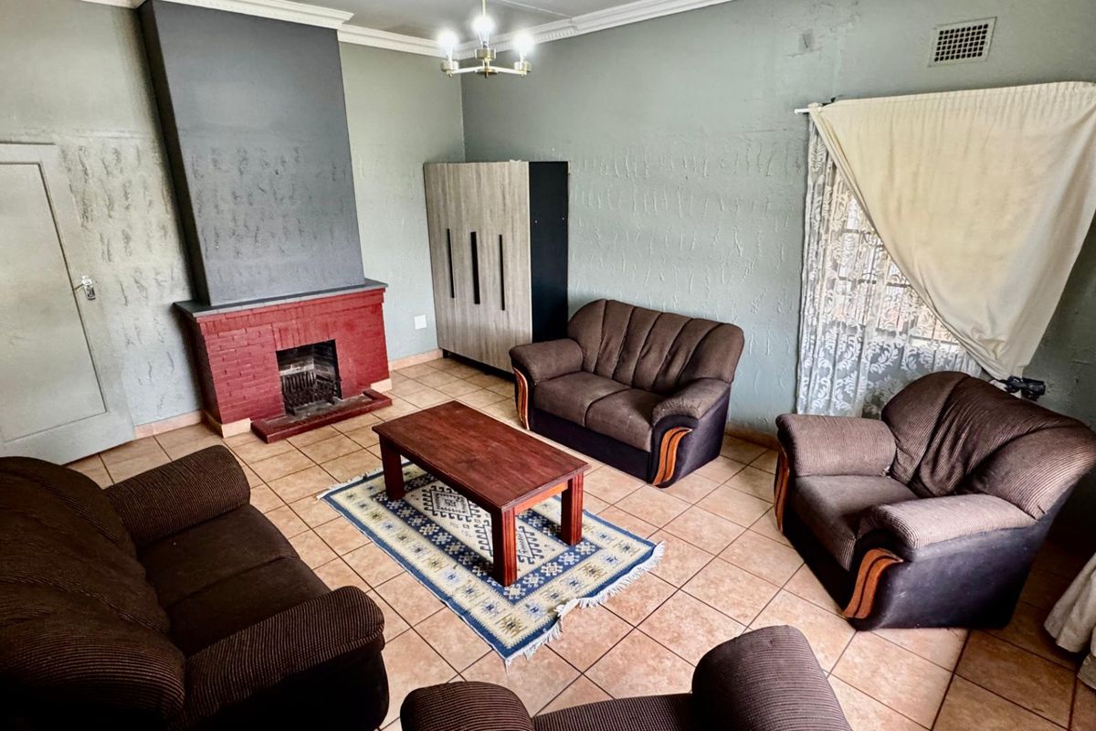 Living room featuring a brick fireplace, tiled flooring, and textured walls, offering a functional space with potential for cosmetic updates.