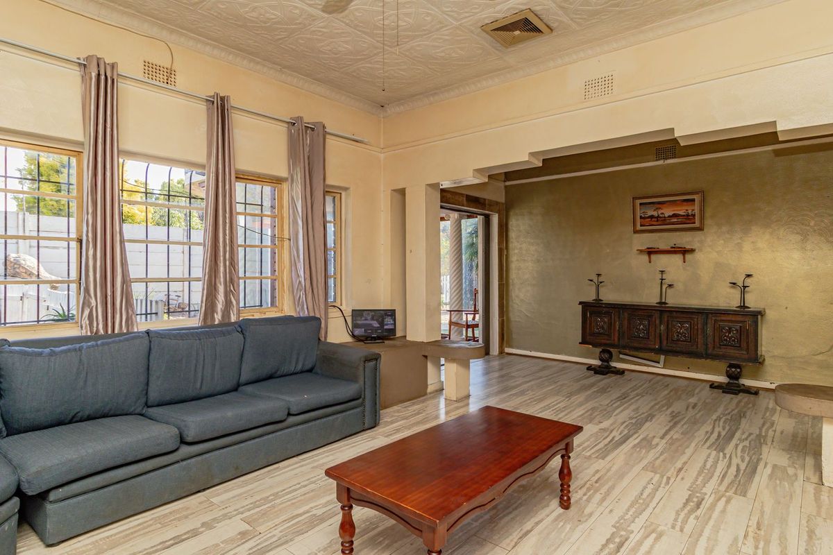 Spacious living room featuring a decorative pressed metal ceiling, tiled flooring, and built-in concrete shelving, offering a classic layout with natural light.