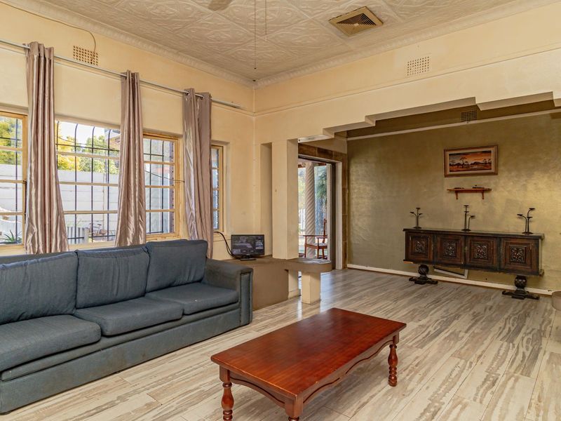 Spacious living room featuring a decorative pressed metal ceiling, tiled flooring, and built-in concrete shelving, offering a classic layout with natural light.