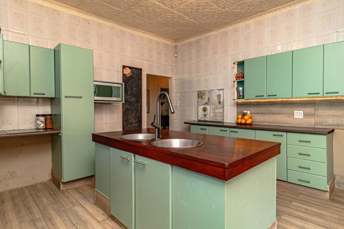 A functional kitchen featuring a central island with a double sink, ample built-in cabinetry, and tiled wall finishes.