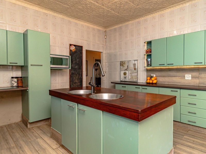 A functional kitchen featuring a central island with a double sink, ample built-in cabinetry, and tiled wall finishes.