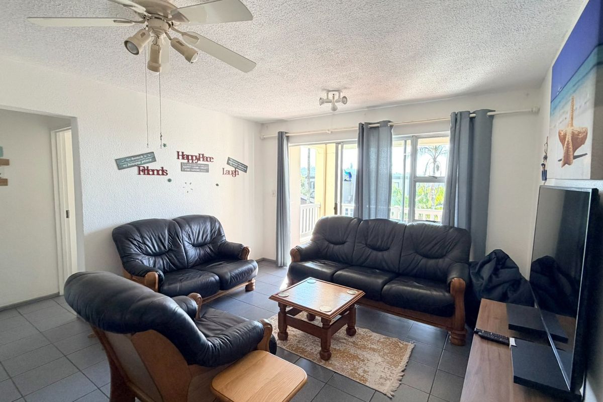 A living room featuring tiled flooring, a ceiling fan, and a sliding glass door providing access to an outdoor area.