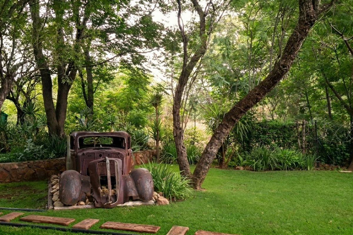 A lush, well-maintained garden area featuring mature trees, a stone retaining wall, and a manicured lawn.