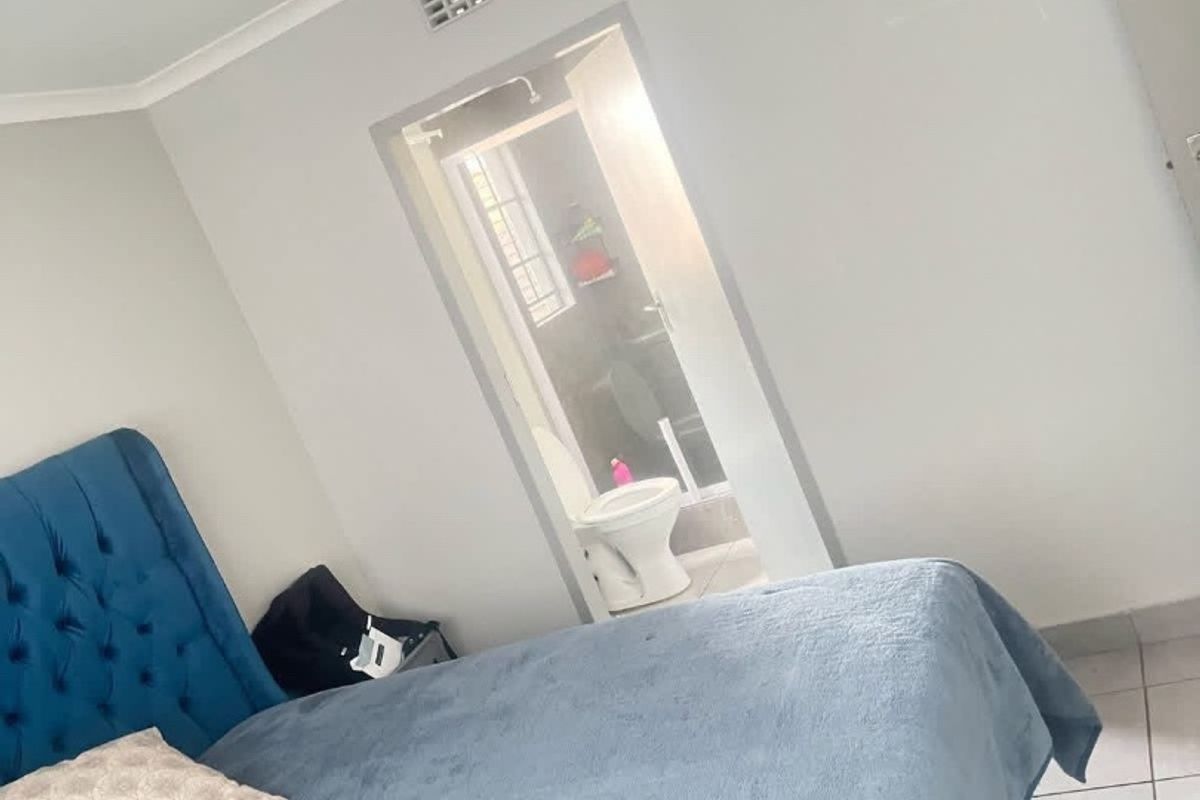 A bedroom featuring tiled flooring and a ceiling light, with a direct view into an adjoining en-suite bathroom.
