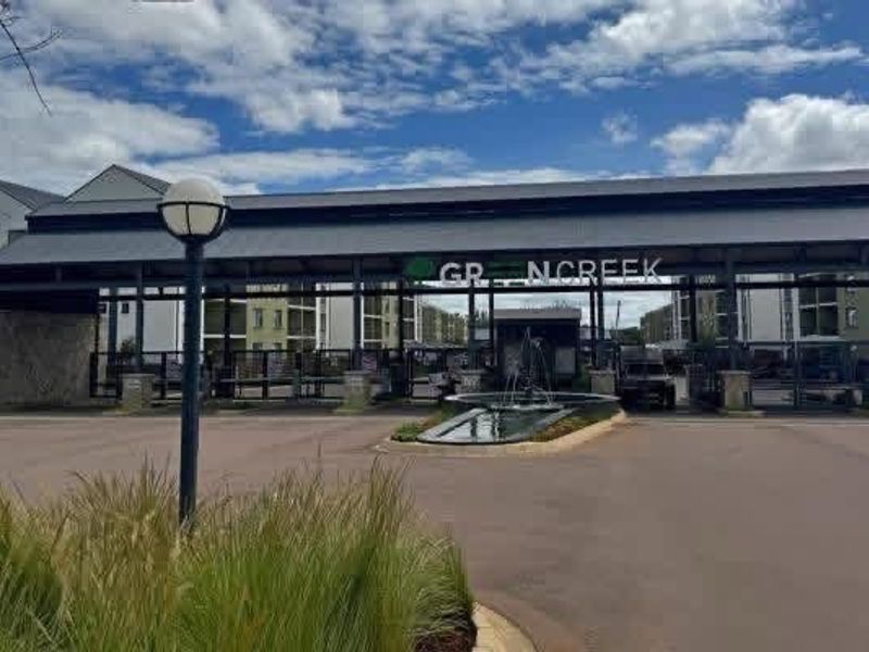 The main entrance to the Greencreek apartment complex, featuring a secure gated access point, guard house, and a landscaped water feature.