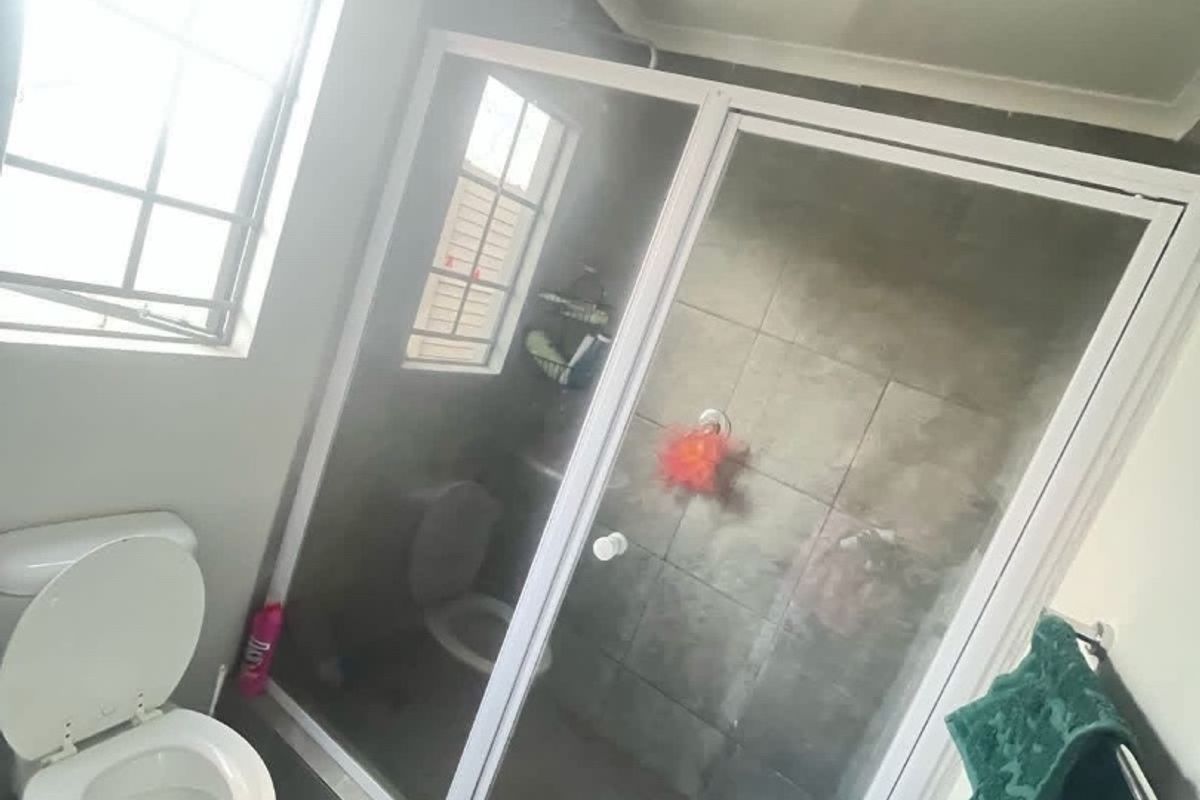 A functional bathroom featuring a glass-enclosed shower, tiled flooring, and standard toilet fixture, offering a clean and practical layout.