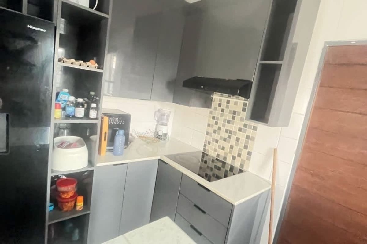 Compact modern kitchen featuring grey high-gloss cabinetry, stone countertops, a built-in electric hob with extractor fan, and a decorative tiled backsplash.