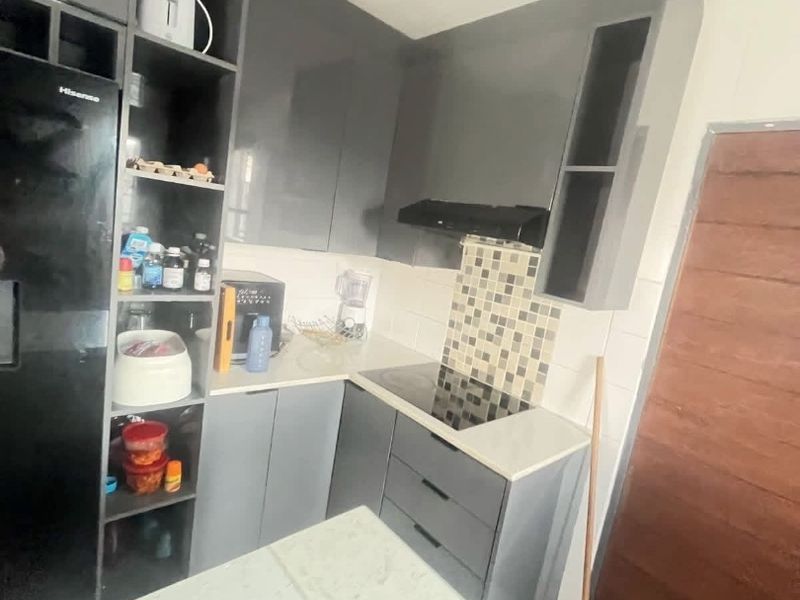Compact modern kitchen featuring grey high-gloss cabinetry, stone countertops, a built-in electric hob with extractor fan, and a decorative tiled backsplash.