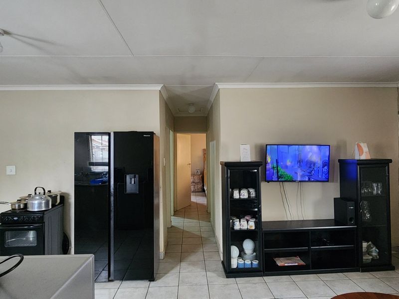 An open-plan living area featuring tiled flooring and neutral wall finishes, providing a functional layout with direct access to the hallway.