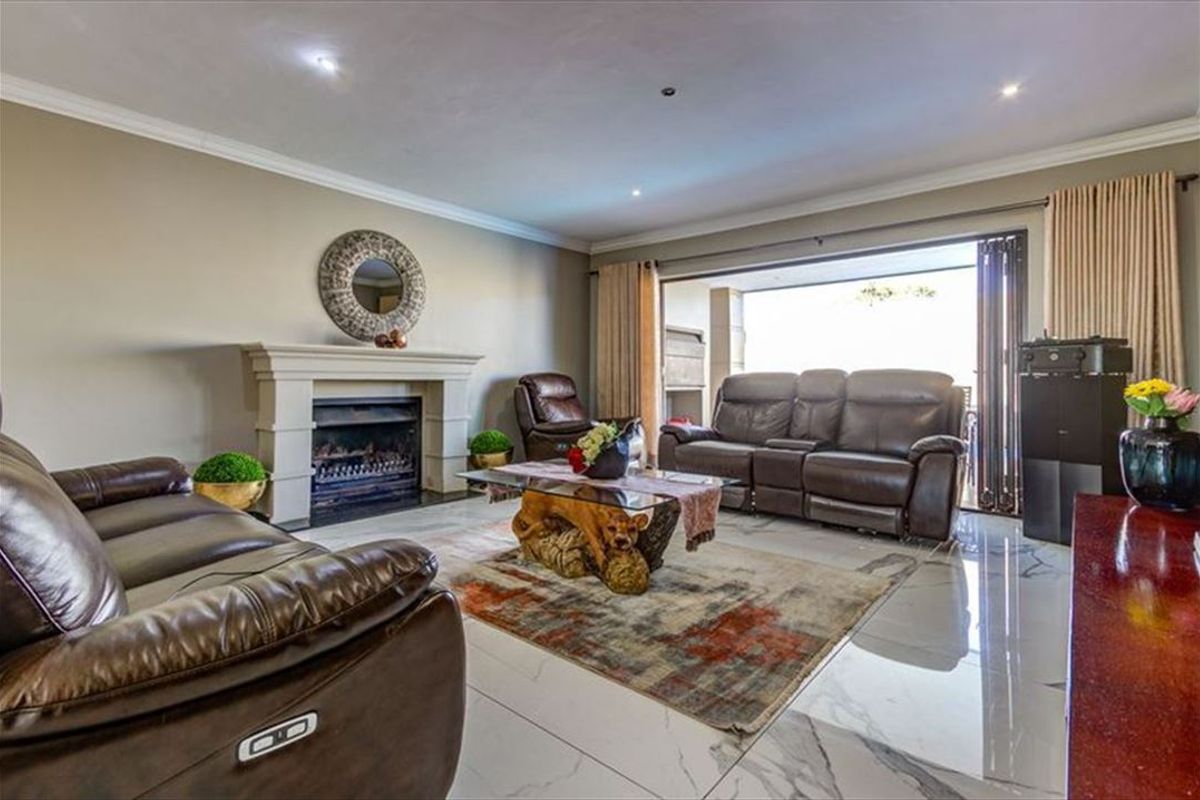 Spacious living room featuring a fireplace, polished tiled flooring, and large sliding stacker doors that open to an outdoor patio area.