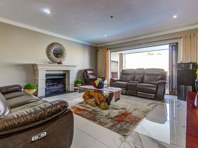 Spacious living room featuring a fireplace, polished tiled flooring, and large sliding stacker doors that open to an outdoor patio area.