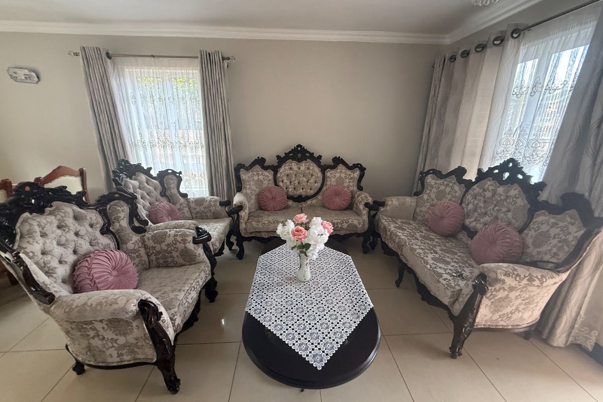 A well-maintained living room featuring neutral tiled flooring, crown molding, and dual window treatments, providing a bright and comfortable space.