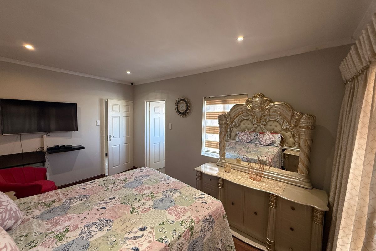 A spacious bedroom featuring laminate flooring, recessed downlighting, and neutral wall finishes, providing a comfortable and functional sleeping area.