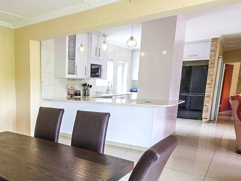 Open plan living and dining area featuring a modern kitchen with stone countertops, breakfast bar, and elegant pendant lighting.