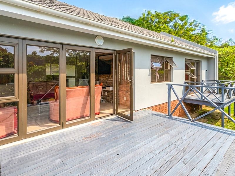 Spacious timber deck featuring a balustrade and direct access to the interior living area through large aluminium stacker doors.