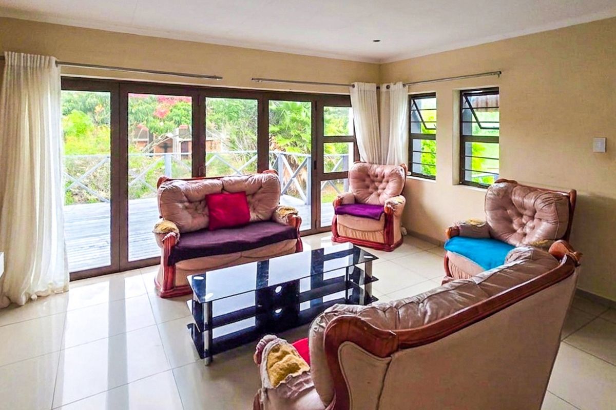 Spacious living room featuring tiled floors, a stone accent wall, and large aluminium sliding doors providing access to an outdoor deck area.