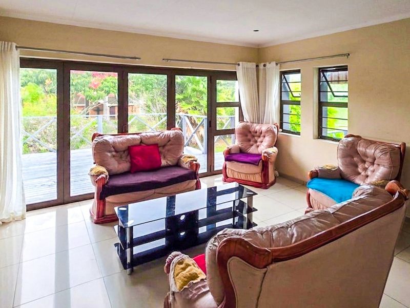 Spacious living room featuring tiled floors, a stone accent wall, and large aluminium sliding doors providing access to an outdoor deck area.