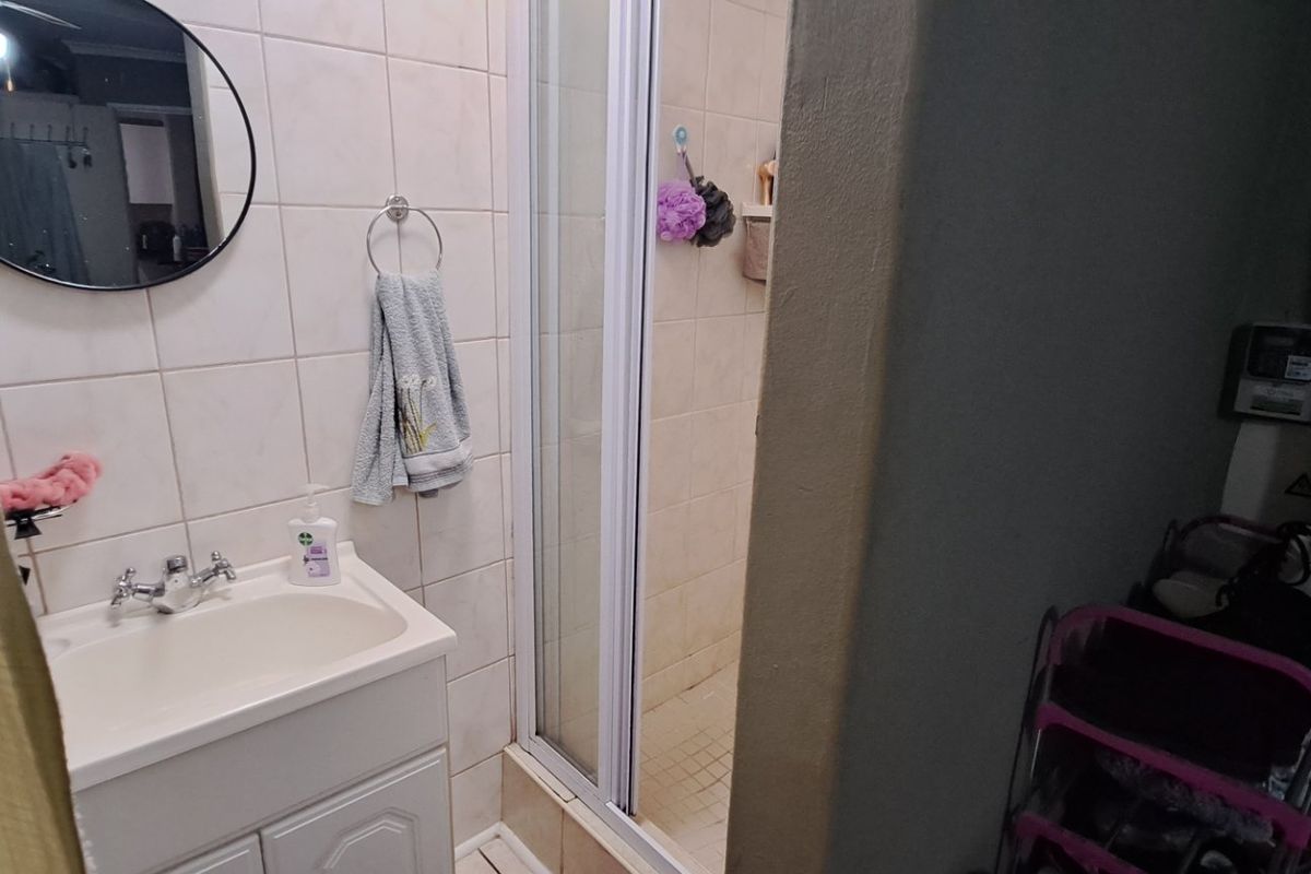 A functional bathroom featuring a vanity basin, shower enclosure with sliding doors, and tiled wall finishes.