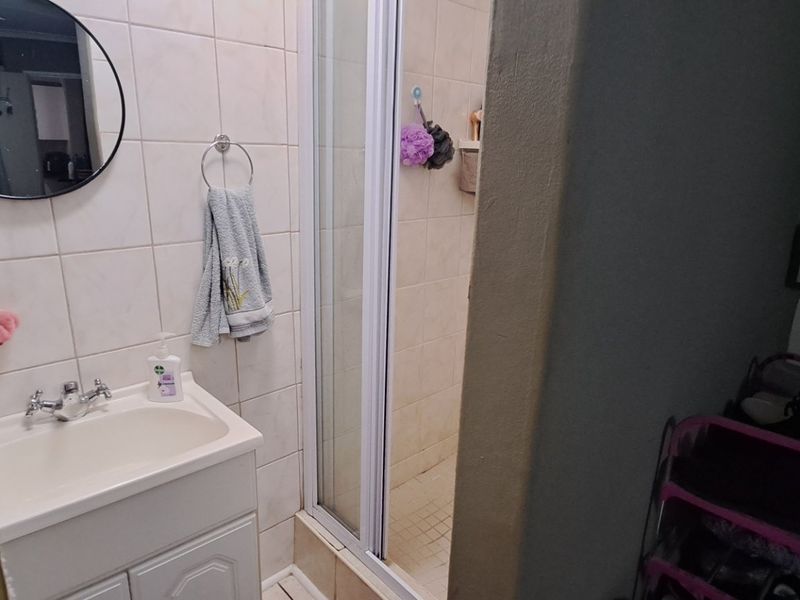 A functional bathroom featuring a vanity basin, shower enclosure with sliding doors, and tiled wall finishes.