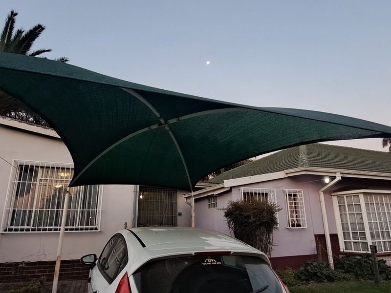 Front exterior view of the property featuring a shade sail carport, security bars on windows, and a tiled roof.