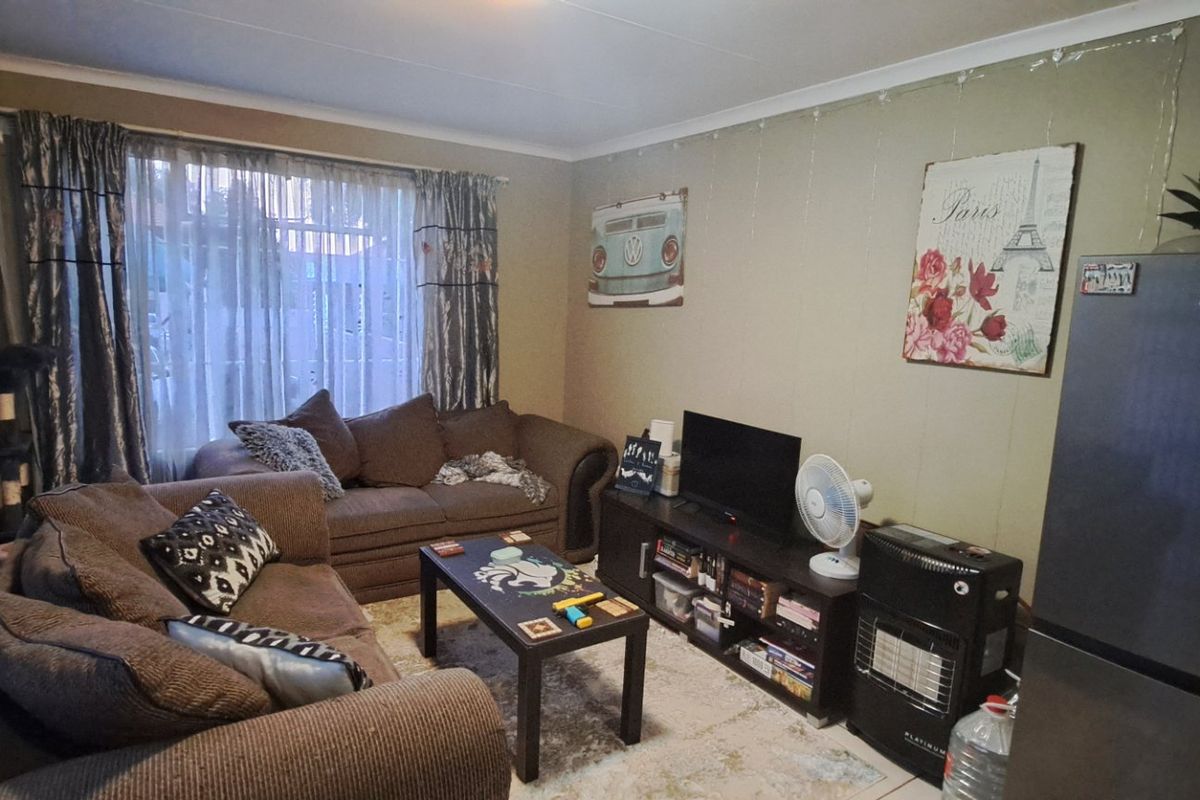 A living room area featuring tiled flooring and curtain rails, providing a functional space for relaxation.
