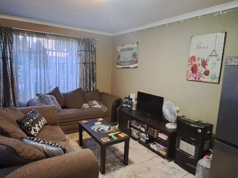 A living room area featuring tiled flooring and curtain rails, providing a functional space for relaxation.