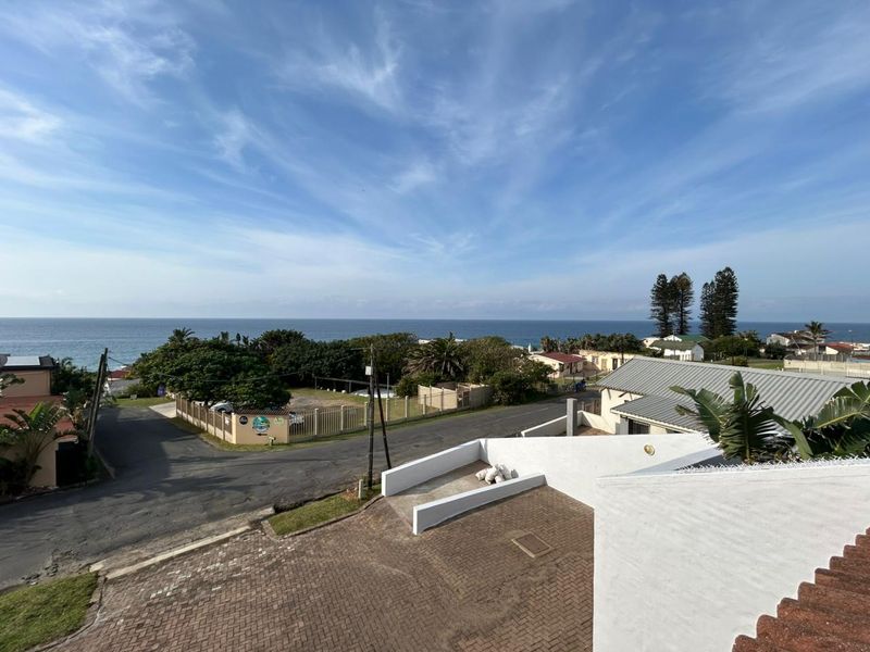 Elevated coastal view overlooking the surrounding neighborhood, paved driveway, and the ocean horizon.