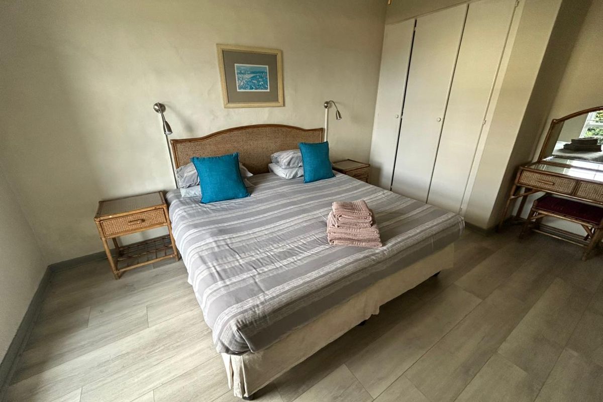 A bedroom featuring light-toned laminate flooring, built-in storage cupboards, and wall-mounted reading lights.