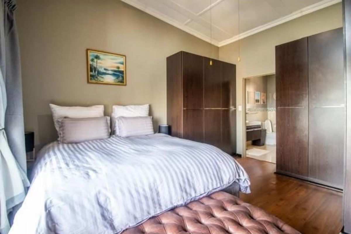A well-maintained bedroom featuring laminate flooring, ample built-in cupboard space, and direct access to an en-suite bathroom.