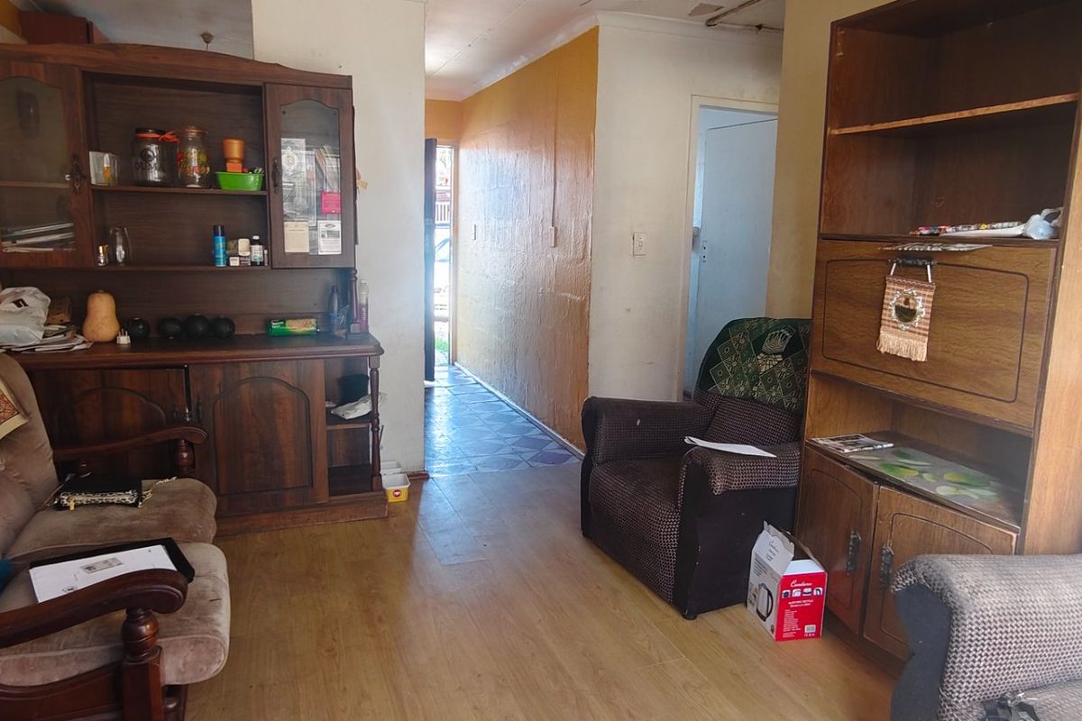 A living room area featuring laminate flooring and coving, showing signs of wear on the wall surfaces.