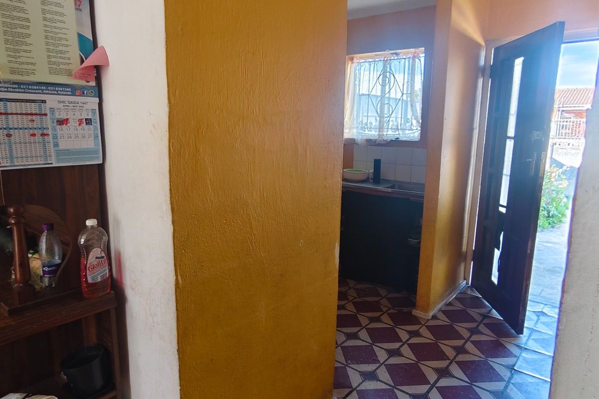 A view into a small kitchen area featuring tiled flooring and direct access to the exterior through a timber door.