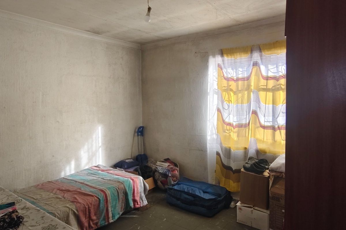 A bedroom space requiring cosmetic updates, featuring visible wall and ceiling wear, suitable for renovation to improve the overall aesthetic.