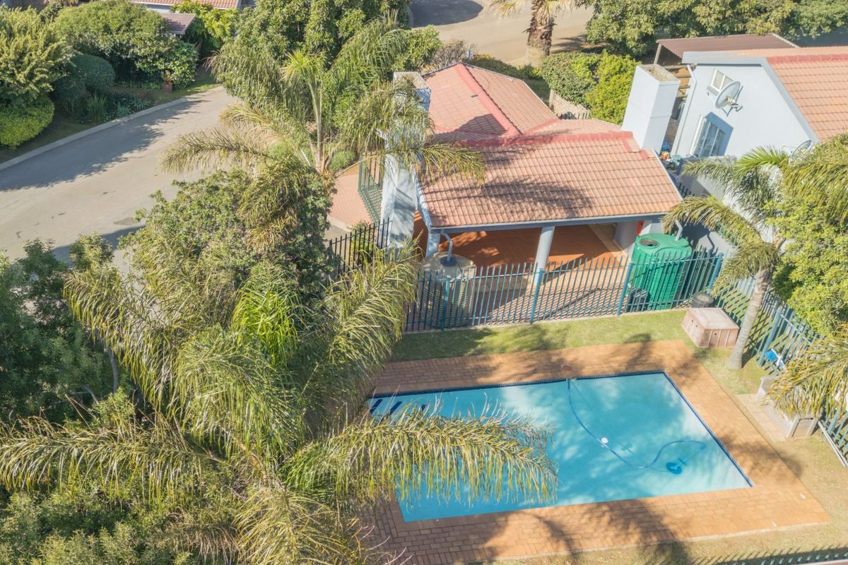 Aerial view of the townhouse property featuring a private swimming pool, paved patio area, and established garden surroundings.