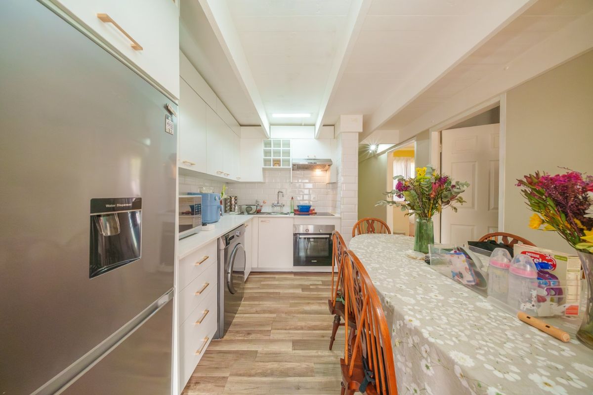 A functional kitchen featuring white cabinetry, subway tile backsplash, integrated oven, and wood-look laminate flooring, providing a clean and practical cooking space.