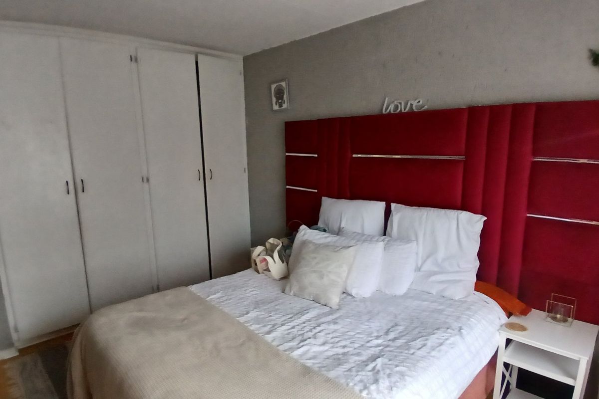 A bedroom featuring built-in cupboards and a grey accent wall.