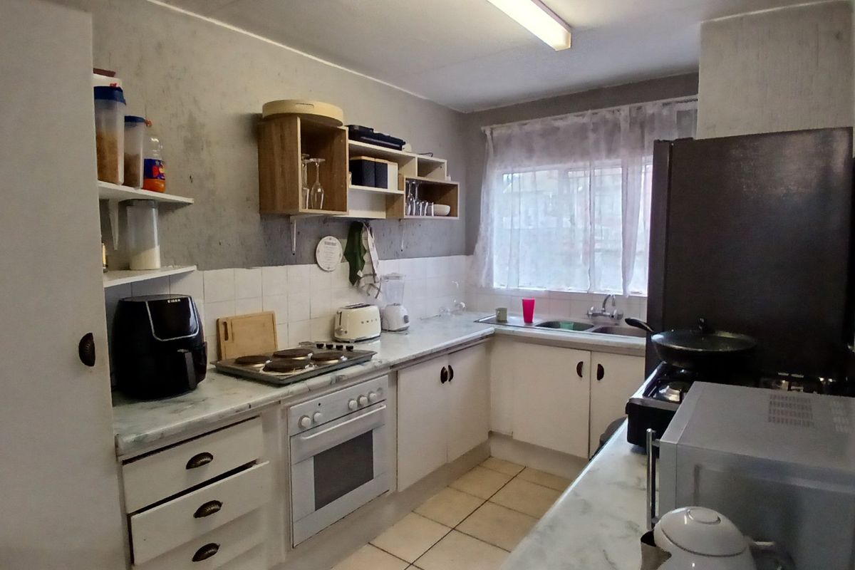 A functional kitchen featuring built-in cabinetry, an electric oven and hob, and a double sink with tiled splashbacks.