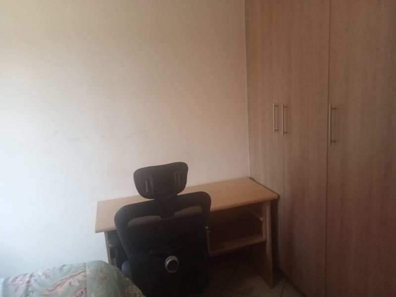 A bedroom featuring a built-in wooden wardrobe with modern handles, providing functional storage space.
