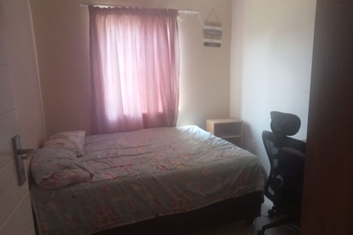 A standard bedroom featuring tiled flooring and a window with curtain treatments.